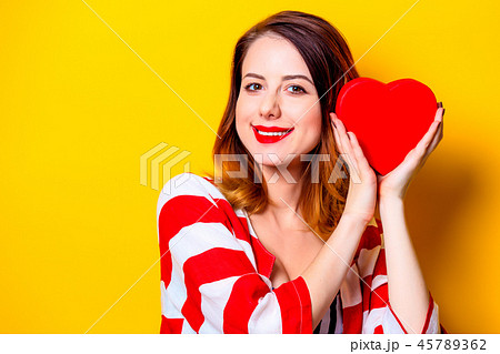 Woman with heart shape box on yellow background Woman with heart shape box on yellow background 45789362