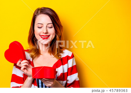 Woman with heart shape box on yellow background 45789363