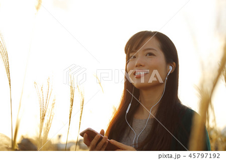 ススキの野原を音楽を聴きながら歩く女性 ススキの野原を音楽を聴きながら歩く女性 45797192
