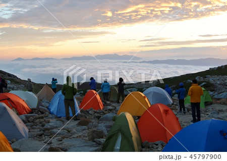 キャンプ場から朝日を見る登山者の写真素材