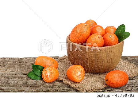 Cumquat or kumquat with leaf in wooden bowl on old wooden table with white background Cumquat or kumquat with leaf in wooden bowl on old wooden table with white background 45799792