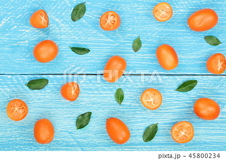 Cumquat or kumquat with leaf on blue wooden background. Top view. Flat lay pattern Cumquat or kumquat with leaf on blue wooden background. Top view. Flat lay pattern 45800234