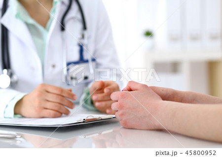 Doctor and patient talking while sitting at the desk in hospital office, close-up of human hands Doctor and patient talking while sitting at the desk in hospital office, close-up of human hands 45800952