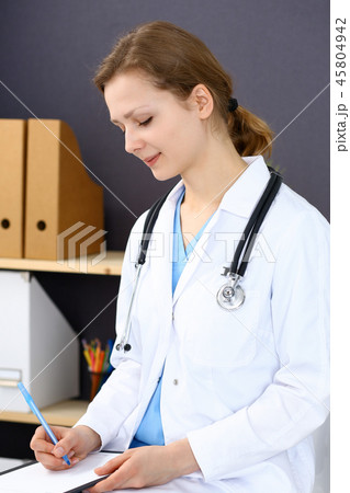 Woman doctor at work at hospital. Young female physician write prescription or filling up medical Woman doctor at work at hospital. Young female physician write prescription or filling up medical 45804942