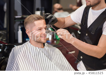Barber removing black mask from face of man in barber shop Barber removing black mask from face of man in barber shop 45811525