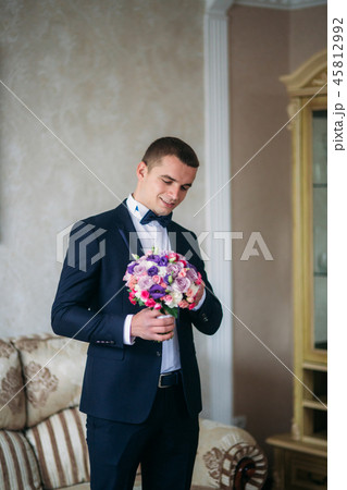 Handsome man in wedding suit hold a bouquet of flowers Handsome man in wedding suit hold a bouquet of flowers 45812992