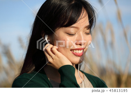 音楽を聴きながらススキの野原を歩く女性 45813195