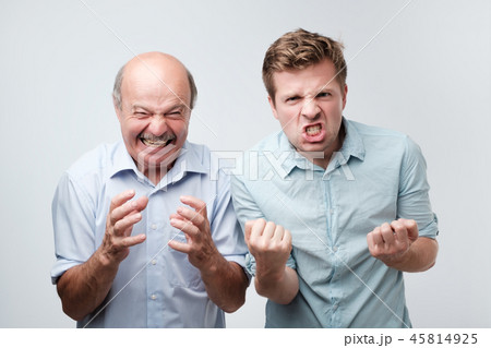 Furious angry two men exclaim with negative emotions shout loudly, over white studio wall Furious angry two men exclaim with negative emotions shout loudly, over white studio wall 45814925