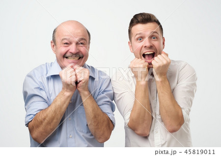 Portrait of a two surprised men father and son or best friends looking at camera with mouth open Portrait of a two surprised men father and son or best friends looking at camera with mouth open 45819011