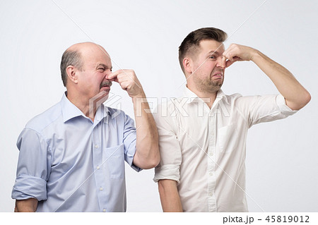 Two men cover their noses due to a bad smell 45819012