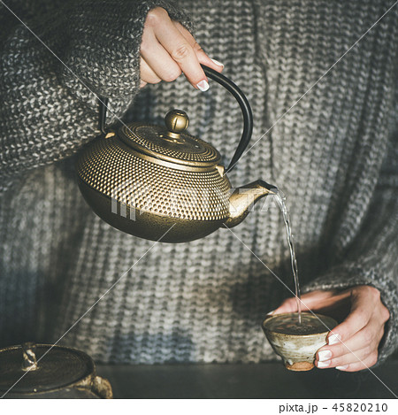 Female pouring green tea from pot into cup, square crop Female pouring green tea from pot into cup, square crop 45820210