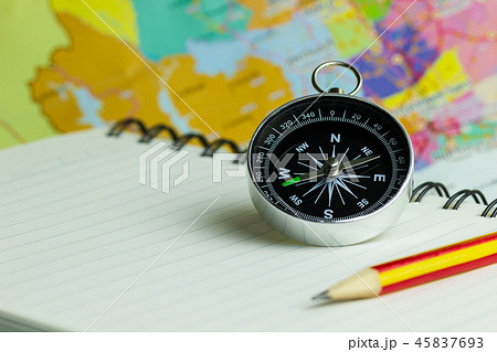 Compass notebook and pencil laid on a paper map. 45837693