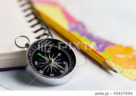 Compass notebook and pencil laid on a paper map. 45837694