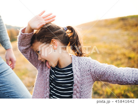 A small girl with unrecognizable father in autumn nature, having fun. 45841642