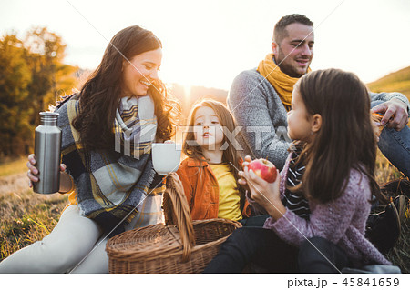 A young family with two small children having picnic in autumn nature at sunset. 45841659