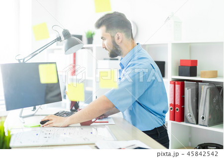A young man stands in the office near a transparent Board with stickers. 45842542