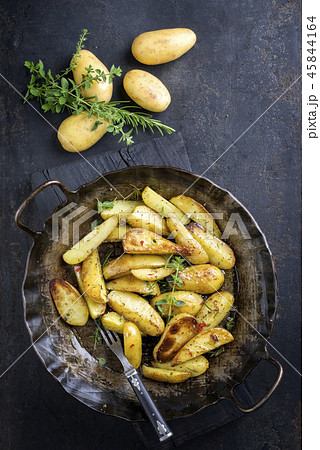 Roast Potatoes with herbs as top view in an iron c Roast Potatoes with herbs as top view in an iron c 45844164