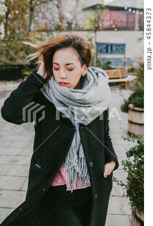 girl in a coat and scarf posing on the street 45844373