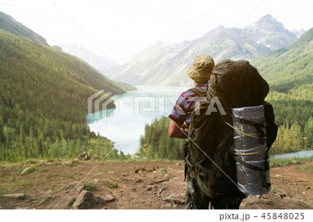 A tourist with a huge backpack looks at the lake. 45848025
