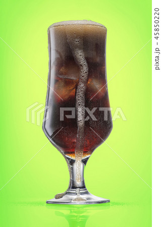 A glass of cola and ice, the drink overflows 45850220