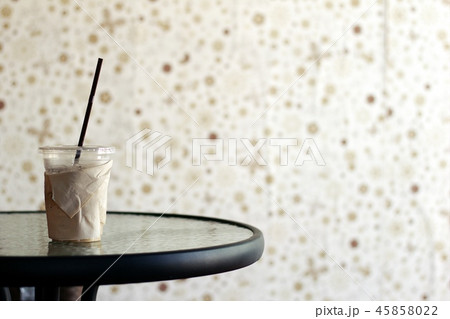 A glass of iced coffee on a glass table with a bro 45858022