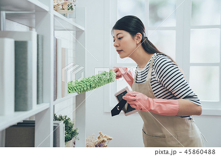 asian housekeeper in apron dusting the bookshelf 45860488
