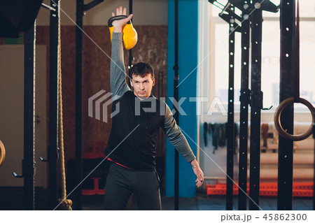 Young man lifting dumbbell and kettlebell at the fitness center. 45862300