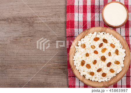 Cottage cheese in bowl with sour cream and raisins on old wooden background with copy space for your 45863997