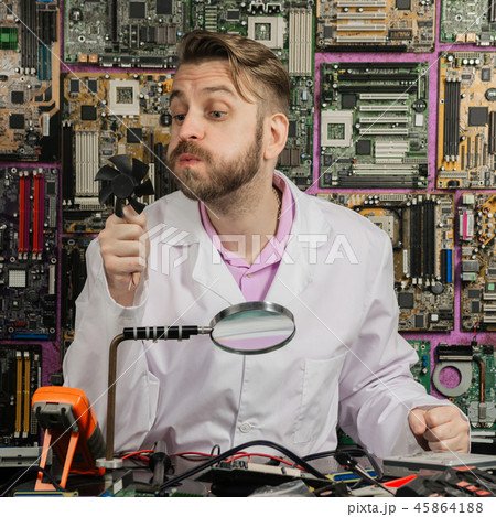 young funny electronics engineer blowing on fan young funny electronics engineer blowing on fan 45864188