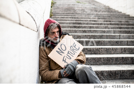 Homeless beggar man sitting outdoors in city holding no future cardboard sign. Homeless beggar man sitting outdoors in city holding no future cardboard sign. 45868544