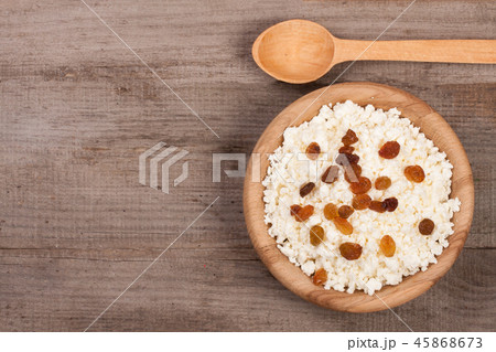 Cottage cheese with raisins in a wooden bowl on old wooden background with copy space for your text Cottage cheese with raisins in a wooden bowl on old wooden background with copy space for your text 45868673
