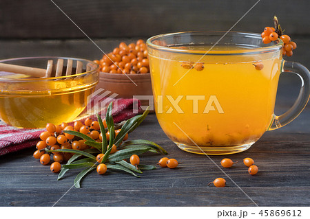 Tea of sea-buckthorn berries with honey and a branch on wooden background 45869612