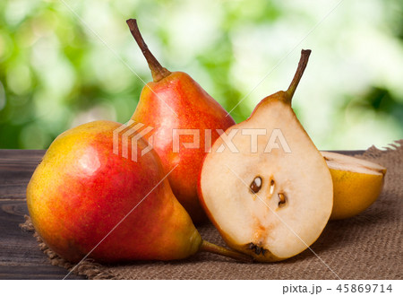 two whole and half of pear on a wooden table with  napkin  burlap 45869714