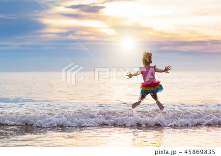 Child playing on ocean beach. Kid at sunset sea. Child playing on ocean beach. Kid at sunset sea. 45869835