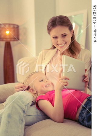 Happy cheerful girl looking at the tablet screen Happy cheerful girl looking at the tablet screen 45870716