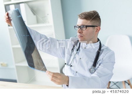 Medicine, healthcare and people concept - Handsome smiling doctor checking x-ray results 45874020