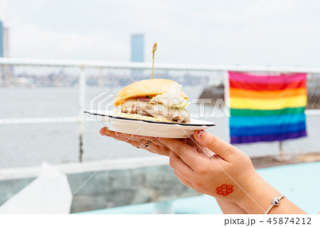 Woman holding burger with rainbow flag on background Woman holding burger with rainbow flag on background 45874212