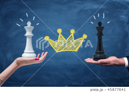A female and a male hands holding a black and a white chess king with a chalk yellow crown drawn 45877641