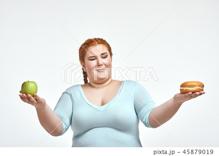 Red haired, chubby woman is choosing between apple and sandwich 45879019