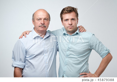 Portrait of mature father and son standing with serious expression on face. Good relatios in family. Portrait of mature father and son standing with serious expression on face. Good relatios in family. 45879388
