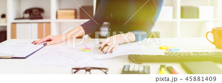 A young girl sits in the office at the table, holds a pen in her hand and fills out the documents. A young girl sits in the office at the table, holds a pen in her hand and fills out the documents. 45881409