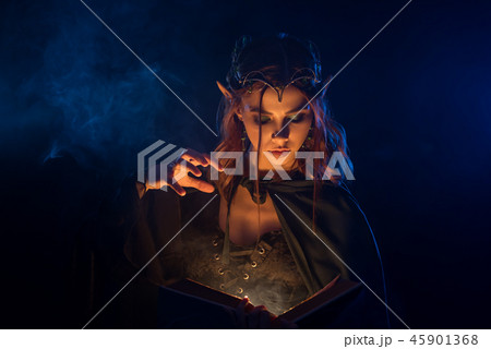 Red haired elf in silver tiara learning spells from book. Red haired elf in silver tiara learning spells from book. 45901368