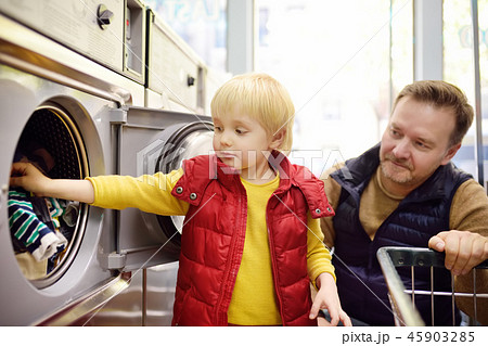 Little boy loads clothes into the washing machine  45903285