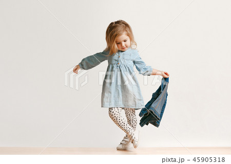 Full length portrait of cute little kid in stylish jeans clothes looking at camera and smiling Full length portrait of cute little kid in stylish jeans clothes looking at camera and smiling 45905318