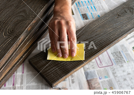 Man's hand with sandpaper polishes board 45906767