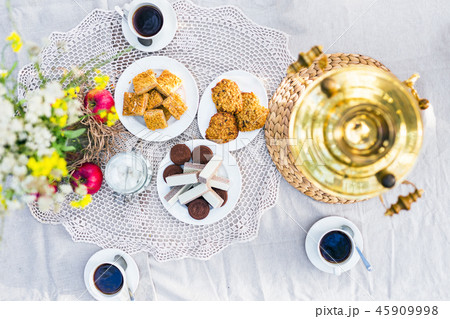 Table with samovar, coffee and sweets decorated with flowers outdoors 45909998