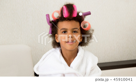 Black girl with curlers with hairpins in her hair. 45910041