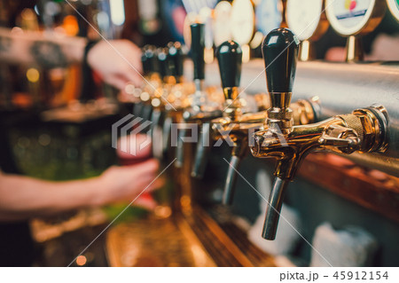 Barman hands pouring a lager beer in a glass. Barman hands pouring a lager beer in a glass. 45912154