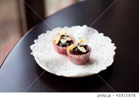 chocolate candy decorated with slices of nuts lying on a white plate chocolate candy decorated with slices of nuts lying on a white plate 45915878