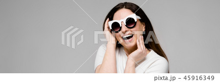 Portrait of emotional beautiful plus size model in sunglasses standing in studio looking in camera Portrait of emotional beautiful plus size model in sunglasses standing in studio looking in camera 45916349